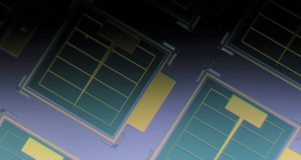 Photo of ultrathin on-chip solar cells. The cells are the green squares and include an ultrathin layer of light-absorbing GaAs, which is key to their radiation tolerance. The surface of each green square is only 120 nanometers, about one-thousandth the thickness of a human hair, above the surrounding gray area. The gold-colored grids are electrically conducting metal contacts. CREDIT: Armin Barthel