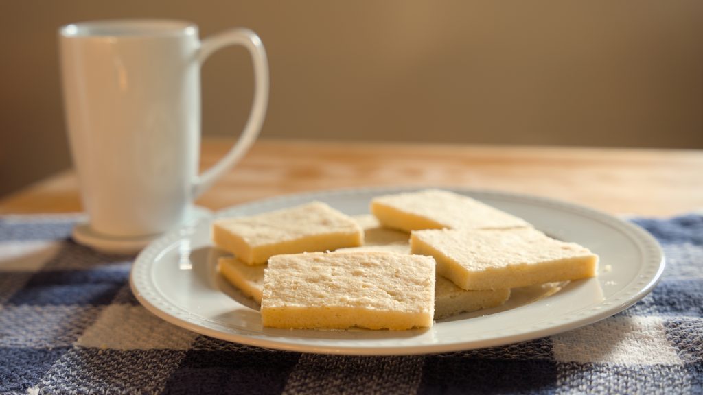 A plate of shortbread next to a ceramic mug