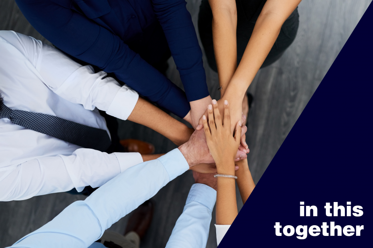 Diverse group of people stacking their hands beside the words “in this together".